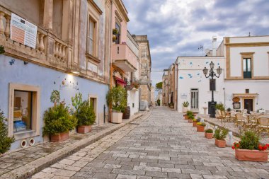Castro di Lecce, İtalya, 18 Mayıs 2018. Puglia bölgesindeki bir kasabada çiçeklerle bezenmiş beyaz boyalı evler arasında dar bir sokak..