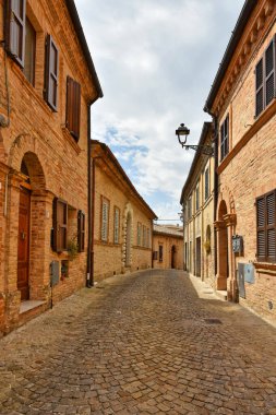 İtalya 'nın Marche bölgesinde bir ortaçağ kasabası olan Montecosaro' nun eski evleri arasında dar bir sokak..