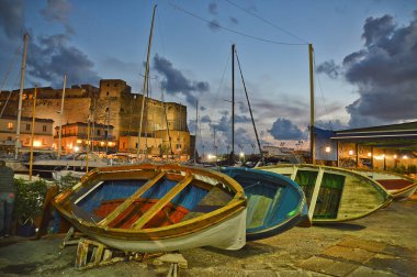 Naples, Italy, 10/10/2016. Fishing boats in the oldest part of the harbor, near a medieval castle.