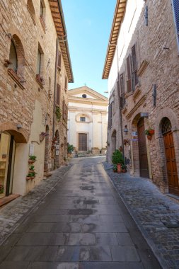 İtalya 'nın Umbria bölgesinde bir ortaçağ köyü olan Spello' nun eski taş evleri arasında bir sokak..