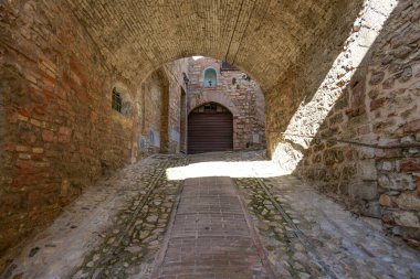 İtalya 'nın Umbria bölgesinde bir ortaçağ köyü olan Spello' nun eski taş evleri arasında bir sokak..