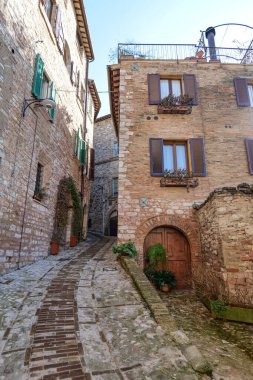 İtalya 'nın Umbria bölgesinde bir ortaçağ köyü olan Spello' nun eski taş evleri arasında bir sokak..