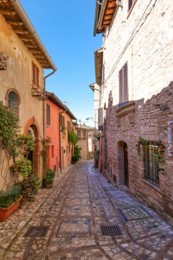 İtalya 'nın Umbria bölgesinde bir ortaçağ köyü olan Spello' nun eski taş evleri arasında bir sokak..
