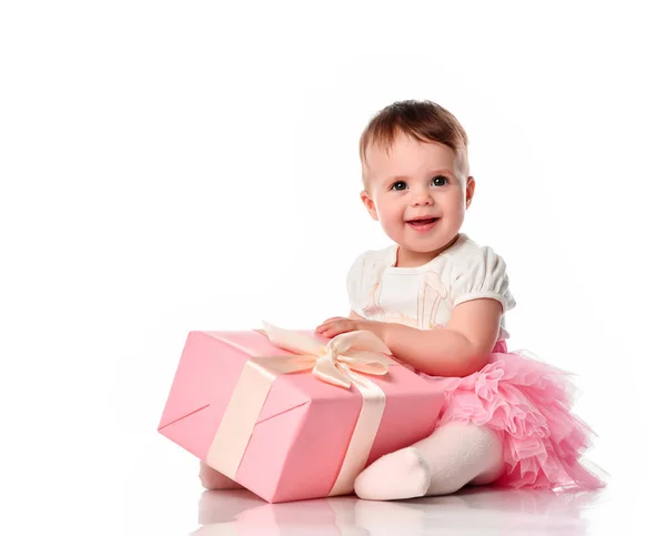 Flicka sitter på golvet med en presentförpackning och ler. — Stockfoto