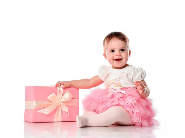 Menina sentada no chão com uma caixa de presente e sorrindo. — Fotografia de Stock