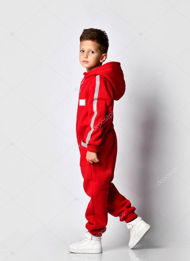 Boy walking in red warm jumpsuit studio shot