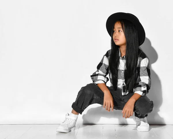 スタイリッシュな小さなアジアの女の子とともに黒髪座っている白い背景と側面を見て. — ストック写真