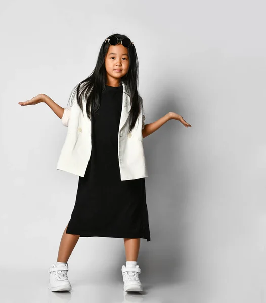Klein aziatisch meisje model poseren in studio op een witte achtergrond met uitgestrekte handen. — Stockfoto