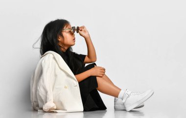 Stüdyoda poz veren, gözlüğünü çıkartan şık bir kızın yan görüntüsü..