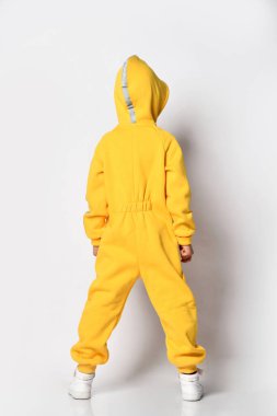 Sarı tulumun arkasını gösteren çocuk.