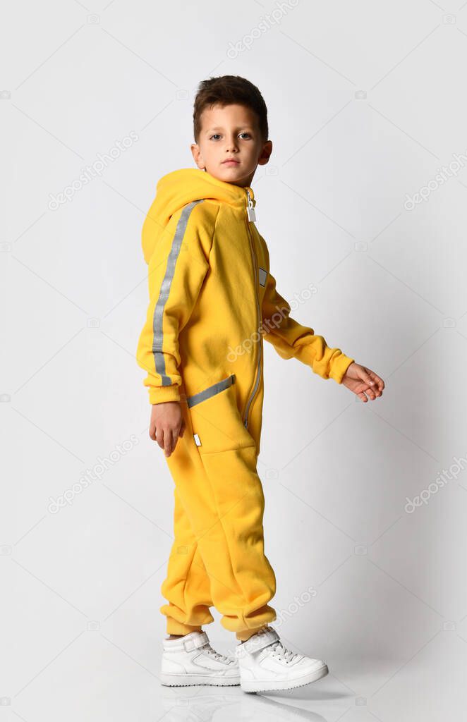 Stylish kid schoolboy in a warm autumn suit, yellow overalls with a zipper