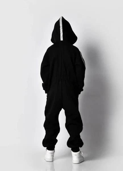 Αγόρι που δείχνει πίσω πλευρά του μαύρου ζεστό jumpsuit — Φωτογραφία Αρχείου