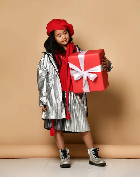 アジアの少女は大きな赤いギフトを持っていますクリスマスや誕生日を記念して与えられた白い弓. — ストック写真
