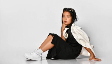 Stüdyoda poz veren, gözlüğünü çıkartan şık bir kızın yan görüntüsü..