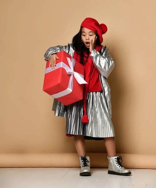 Aziatisch meisje met een groot rood cadeau met een witte strik gegeven ter ere van Kerstmis of verjaardag. — Stockfoto