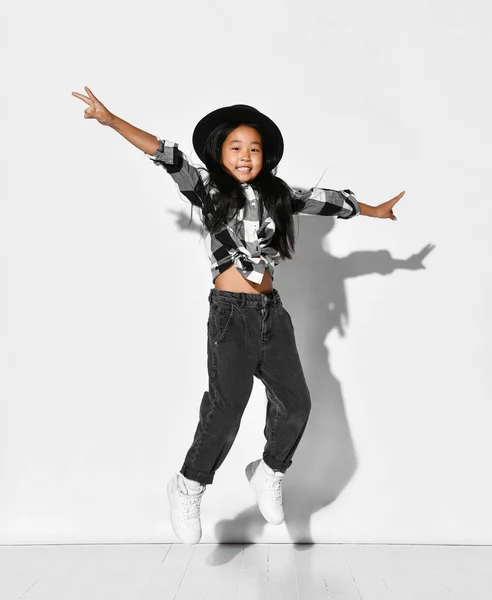 Korean little girl with black hair has fun and jumps with arms outstretched on a white background. — ストック写真