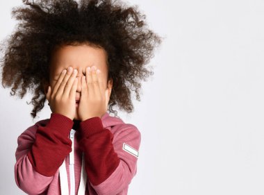 Korkmuş küçük Afrikalı çocuğa yaklaşın utangaç ya da korkmuş yüzünü ellerinizle kapatın..