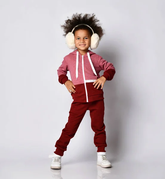 Happy smiling African American girl posing in warm headphones and sportswear. Stock Photo