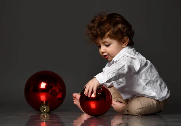 Bebê criança brincando com árvore de natal bolas de vidro vermelho rolando no chão — Fotografia de Stock