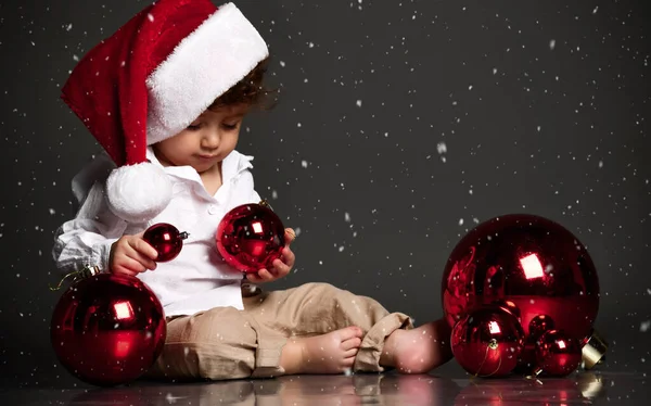 Bebê em chapéu de Santa com ornamento de Natal no espaço de cópia nevado — Fotografia de Stock