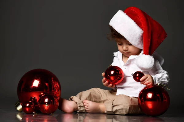 Menino com chapéu de Papai Noel e bolas de Natal — Fotografia de Stock