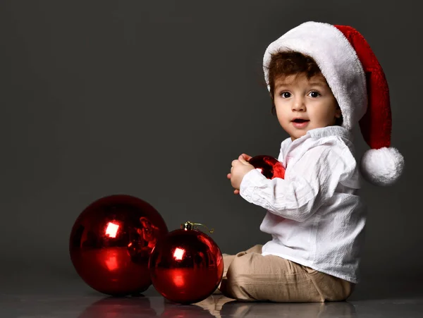 Menino com chapéu de Papai Noel e bolas de Natal — Fotografia de Stock