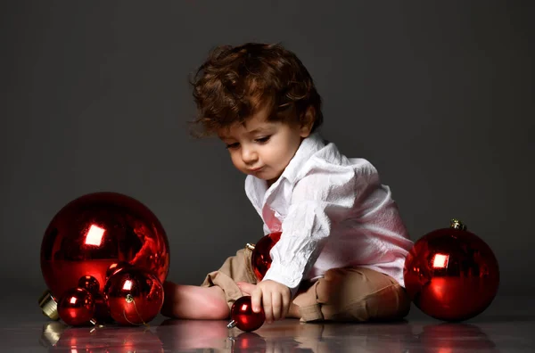 Bebê criança brincando com árvore de natal bolas de vidro vermelho rolando no chão — Fotografia de Stock