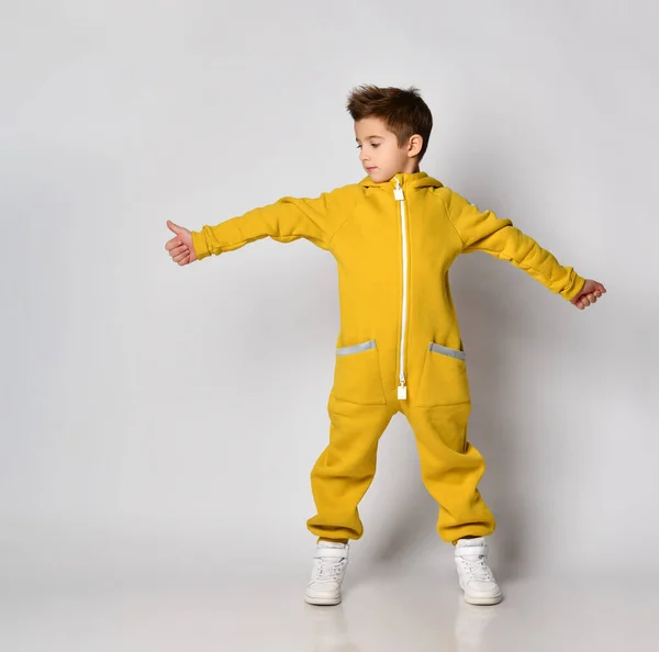 Chlapec ve žlutém sportovním oblečení ukazující palec nahoru a dívající se stranou — Stock fotografie