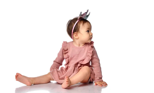 Little cute baby in a crown-shaped headband sits on a gray background. dad and mom princess — Stock Photo, Image