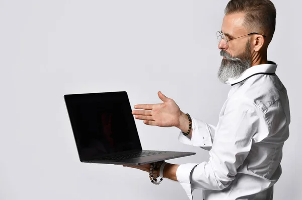 Elegante hombre hipster barbudo en gafas que apuntan a la computadora portátil — Foto de Stock