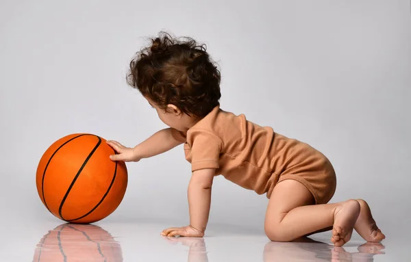 관심을 가진 보디 복을 입은 사내 아이가 회색 바탕에서 농구를 한다. — 스톡 사진