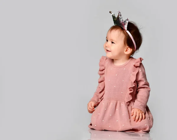 Μικρό χαριτωμένο μωρό σε σχήμα στέμματος στο κεφάλι κάθεται σε ένα γκρι φόντο. μπαμπάς και μαμά πριγκίπισσα — Φωτογραφία Αρχείου