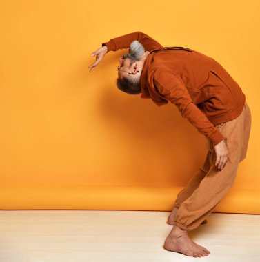 Güçlü sakallı adam stüdyoda geriye doğru eğiliyor.