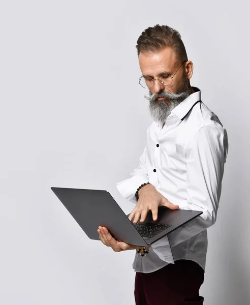 Retrato de estudio de un hombre hipster de mediana edad sosteniendo un portátil y mirando a la cámara. — Foto de Stock