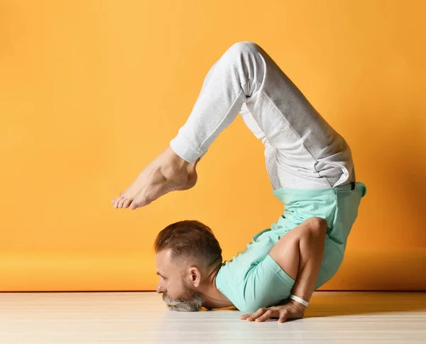 Uomo maturo sportivo che pratica yoga in Vrischikasana scorpione asana — Foto Stock