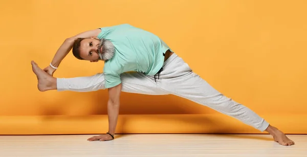 Uomo maturo praticare yoga bilanciamento su una gamba e un braccio — Foto Stock