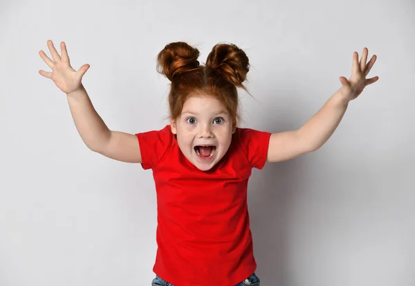 Klein meisje met sproeten en rood haar schreeuwt met haar mond wijd open en armen omhoog. — Stockfoto