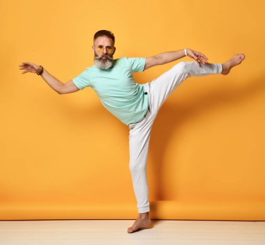 Sağlıklı sakallı bir adam tek bacaklı portrede dengede duruyor.