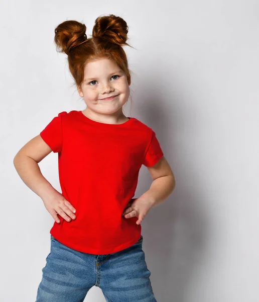 Klein mooi meisje met rood haar en sproeten houdt haar handen op haar taille en kijkt weg. — Stockfoto