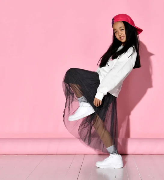 サイドビューの小さな韓国の女の子モデルposingでザ · スタジオ上のピンクの背景上昇彼女の足. — ストック写真