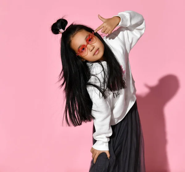 Portrait of a little Korean model girl who is professionally posing on a pink background.