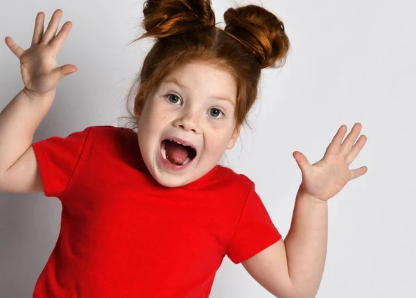Klein meisje met sproeten en rood haar schreeuwt met haar mond wijd open en armen omhoog. — Stockfoto