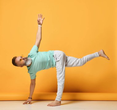 Ardha Chandrasana pozunda yoga yapan olgun bir adam.