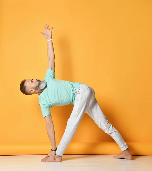 Maduro homem de pé no Utthita Trikonasana ioga pose — Fotografia de Stock