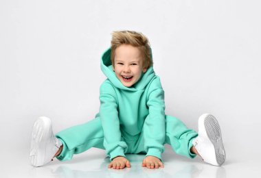 Sıcak spor takım elbiseli ve spor ayakkabılı oyuncu gri bir duvarın arkasında oturuyor..