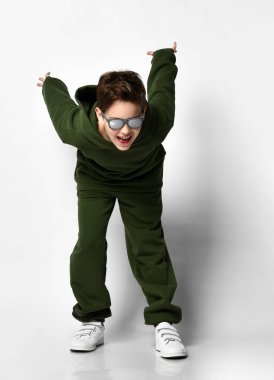 Eşofmanlı, beyaz spor ayakkabılı, beyaz arka planda zıplamak üzere olan havalı bir çocuk. Modern çocuklar için spor ve sağlıklı aktiviteler kavramı. Metin için yer.