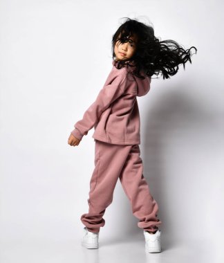 Modern sweatshirt ve pantolon giyen mutlu Asyalı kızın tam portresi.