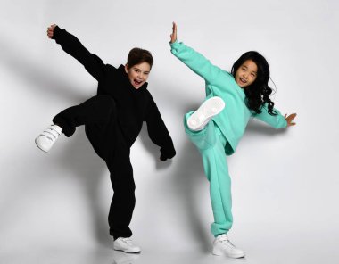 Modaya uygun ırklar arası sportif erkek ve kız yüksek tekme bacak portresiyle zıplıyorlar.