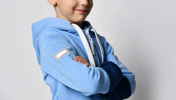Foto recortada de niño en suéter sudadera con capucha de pie con el brazo cruzado contra el fondo blanco —  Fotos de Stock