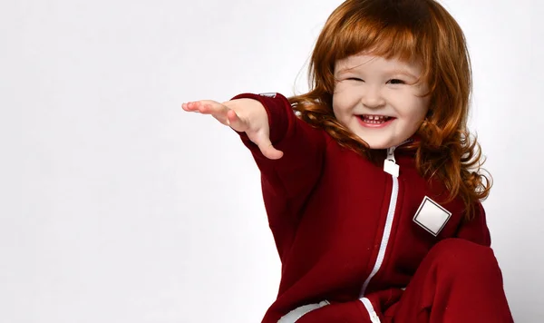 Schattig rood haar meisje zit op een knie en reikt uit naar u met haar hand — Stockfoto